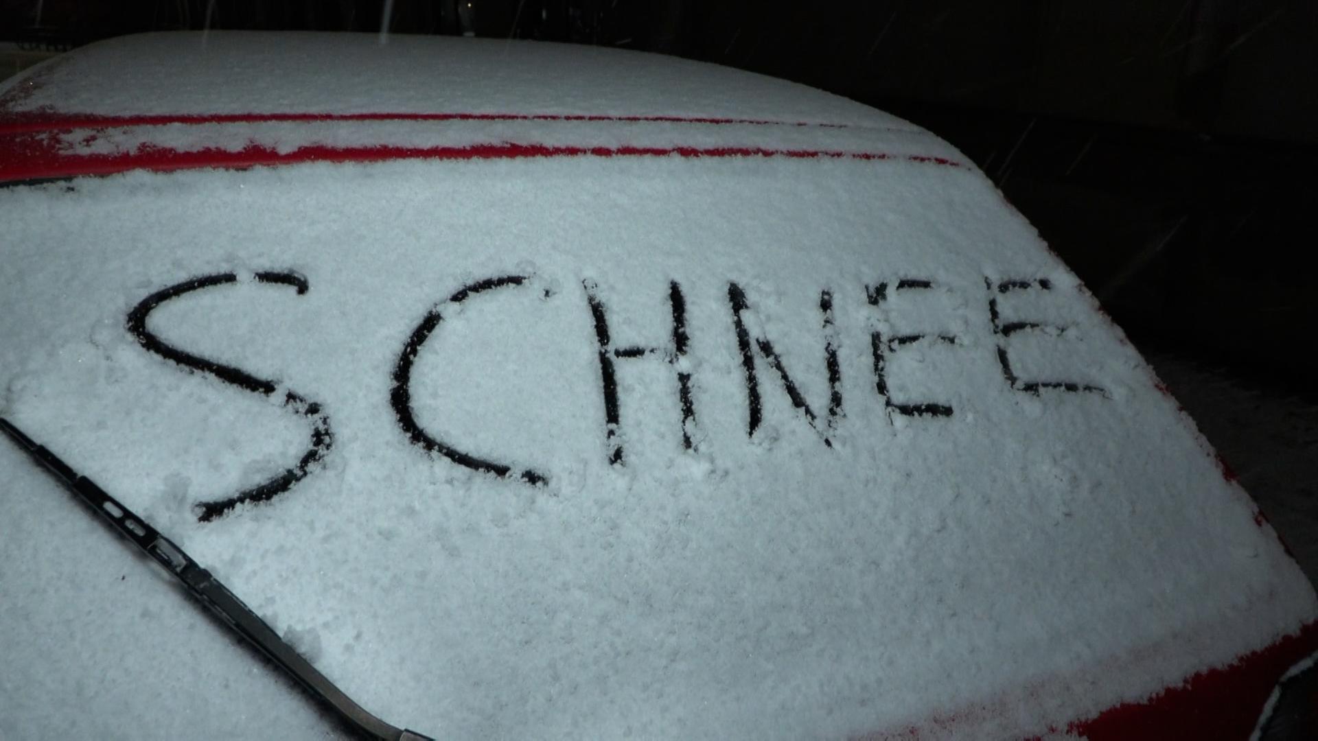Auf der verschneiten Heckscheibe eines Autos steht 