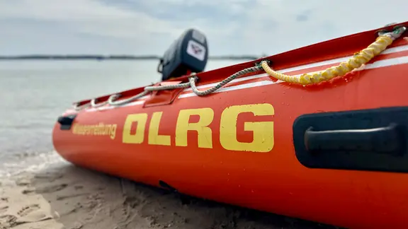 Ein Schlauchboot mit dem Schriftzug DLRG an der Seite liegt an einem Strand.