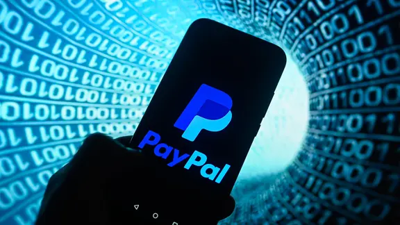 Auf einem Smartphone wird ein Paypal-Logo mit Binärcode im Hintergrund angezeigt.