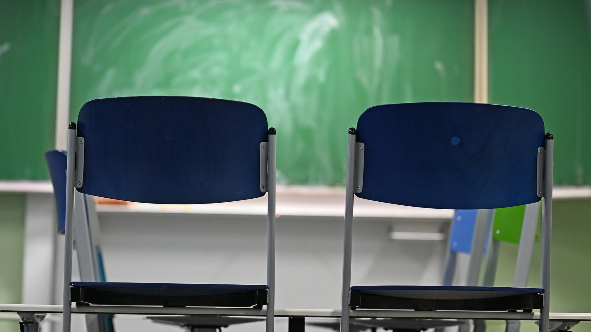 Zwei leere Stühle stehen in einem Klassenraum vor einer Tafel. (Themenbild) | dpa, Michael Brandt