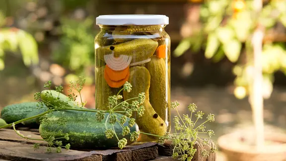 Gewürzgurken in einem Glas auf einem Holzbrett. | Colourbox, aaron007 Gewürzgurken in einem Glas auf einem Holzbrett.