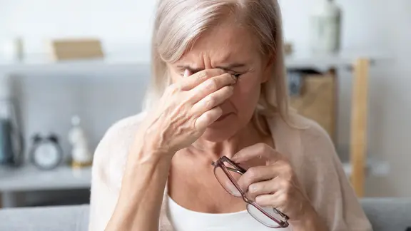 Eine ältere Frau reibt sich die Augen
