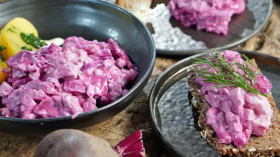 Roter Heringssalat in einer Schüssel und auf einer Scheibe Vollkornbrot