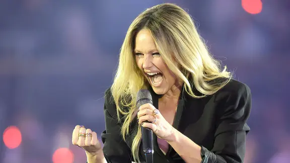 Die Sängerin Helene Fischer mit langen offenen Haaren ballt die Faust und hält beim Singen ein Mikrofon beim Auftritt
