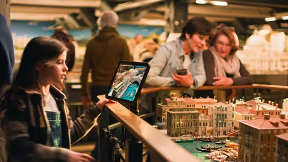 Ein Mädchen sieht sich auf einem Tablet im Miniatur Wunderland eine Simulation zum Kimawandel an.