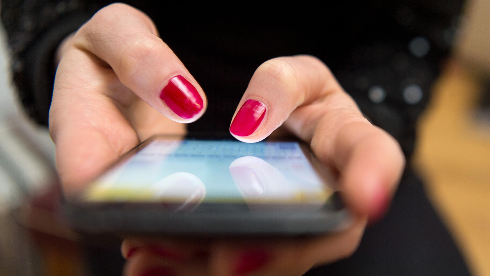 Eine Frau tippt auf einem Smartphone. | Sebastian Gollnow/dpa