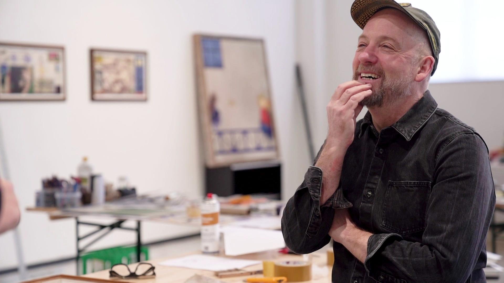 Der Maler Kasper Eistrup, im Hintergrund einige seiner Werke | Screenshot