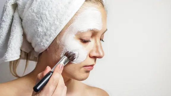 Eine Frau trägt eine Gesichtsmaske auf.