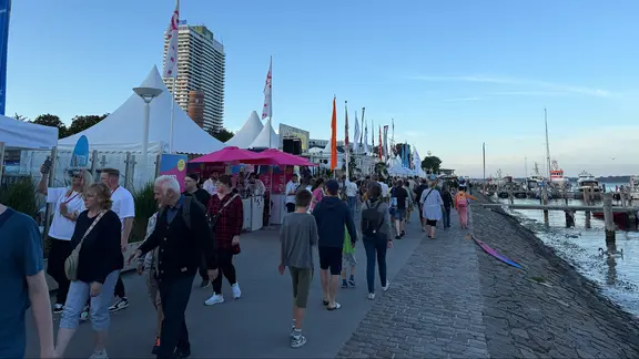 Menschen gehen an einem Kai entlang.