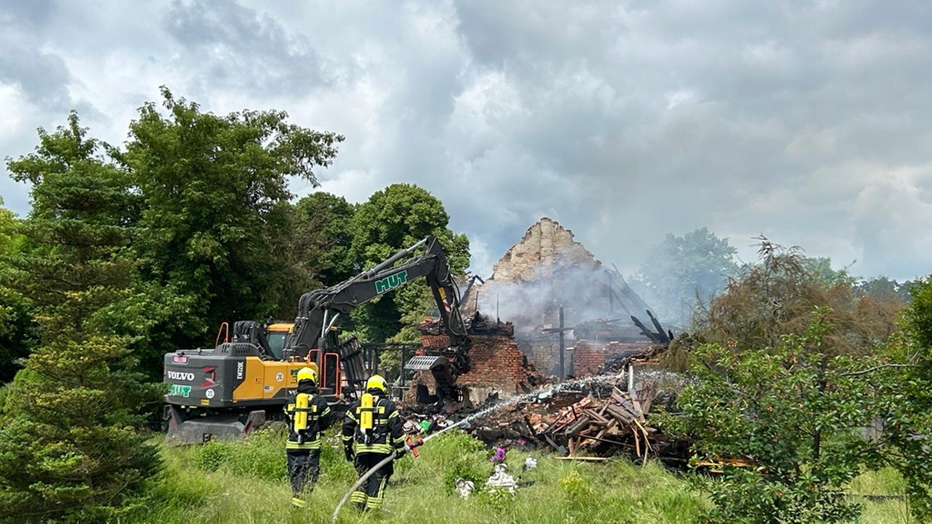 Feuerwehrleute löschen. Im Hintergrund ein heruntergebranntes Haus. | NDR