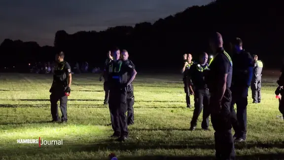 Mehrere Polizeikräfte stehen auf einer Wiese im Stadtpark.