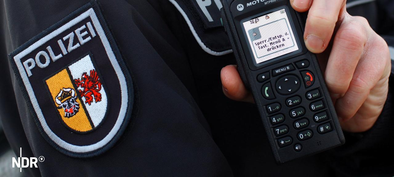 Ein Polizist hält ein Funkgerät.