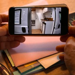 Auf einem Handy wird ein Video gezeigt von einem ausgebauten Wohnmobil.