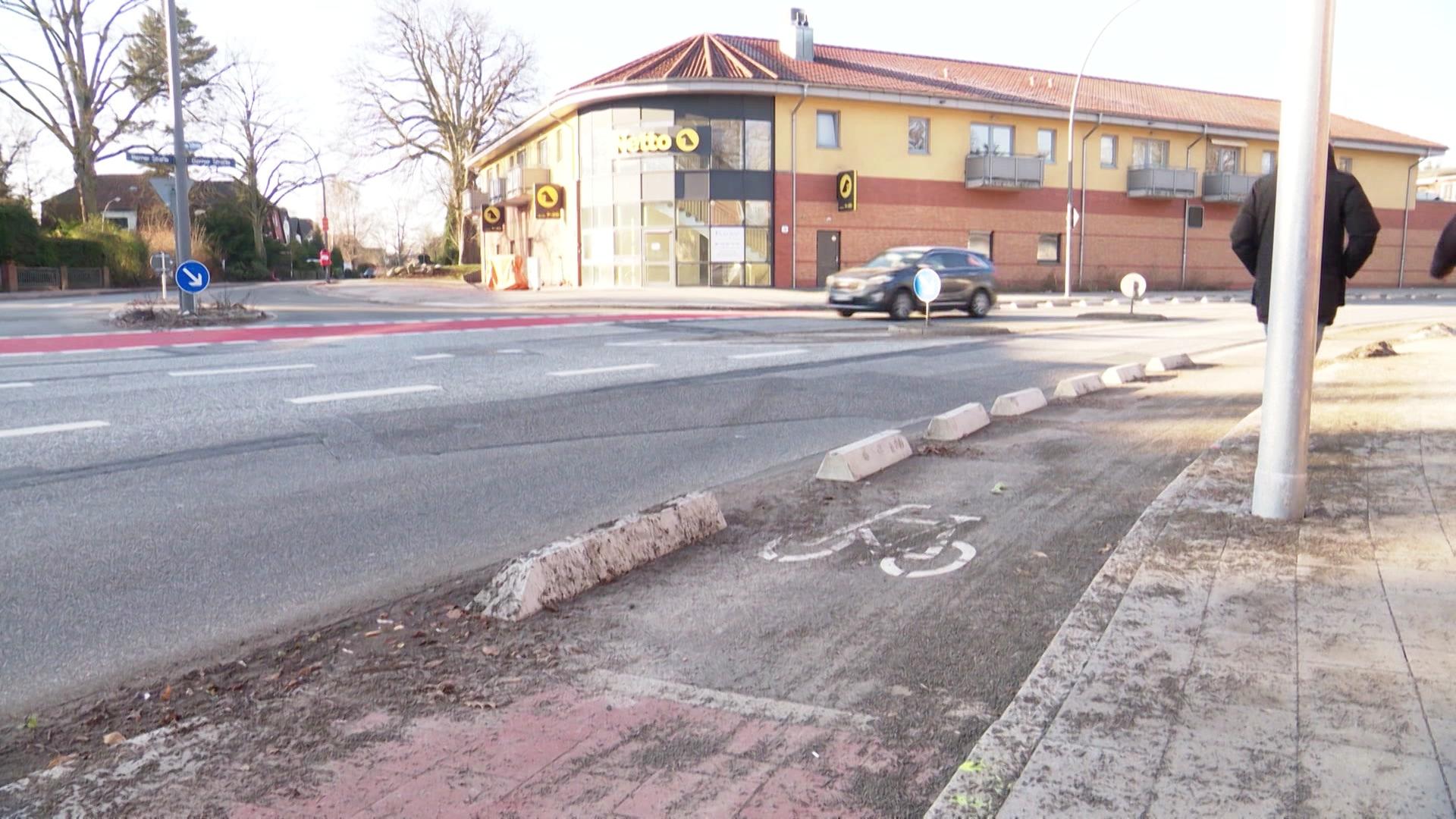 Straßenecke mit Gehweg, im Hintergrund ein Gebäude mit gelbem Logo. | Screenshot