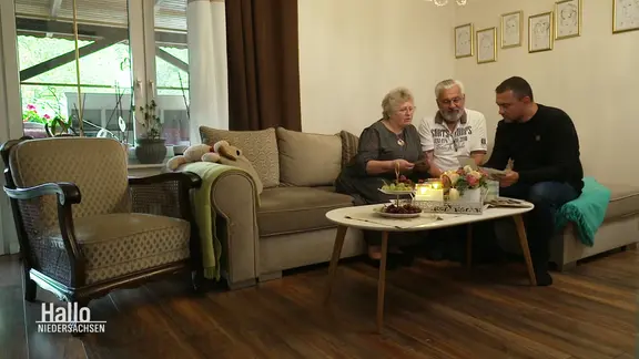 Familie Malsam sitzt auf der Couch und schaut sich Fotos an.