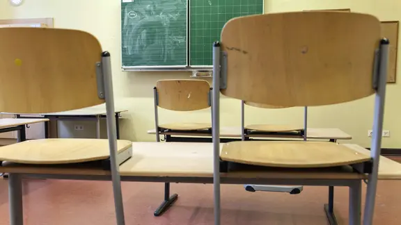 In einem Klassenraum stehen die Stühle auf den Tischen.