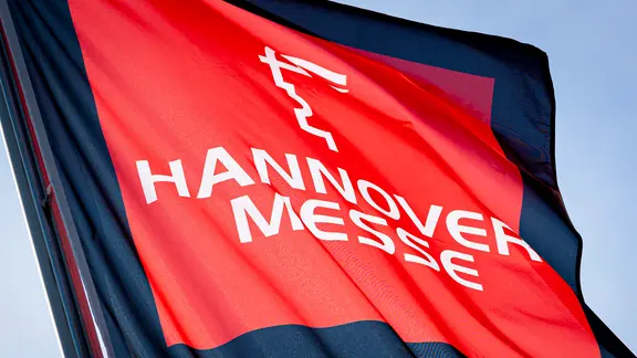Eine Fahne zur Hannover Messe weht im Licht der Sonne auf dem Messegelände.