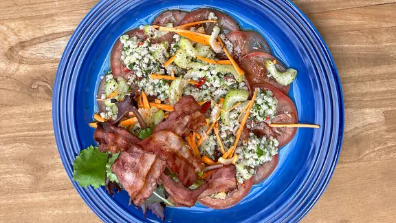 Tomaten-Graupensalat mit krossem Speck auf einem Teller serviert