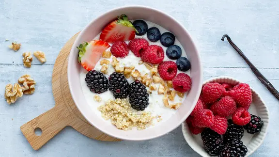 Eine Bowl mit frischen Beeren, Quinoa und gehackten Nüssen.