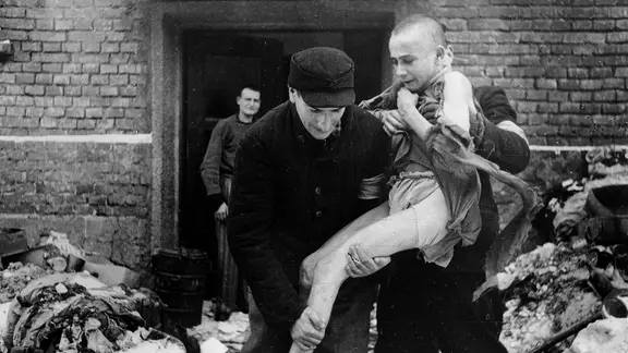 Nach der Befreiung des Konzentrationslagers Auschwitz durch die Rote Armee tragen Angehörige des Roten Kreuzes einen Jugendlichen aus dem Vernichtungslager.