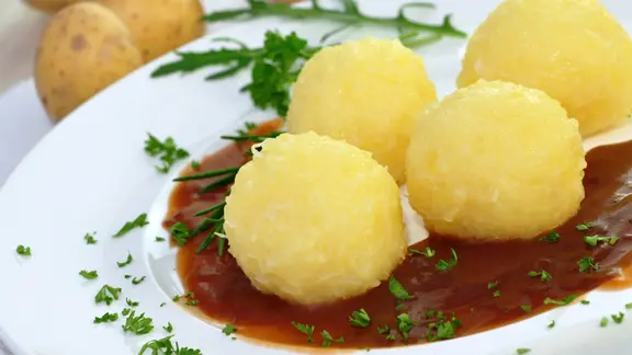 Klöße liegen mit Soße und Petersilie angerichtet auf einem Teller. | photocrew / fotolia, photocrew Klöße liegen mit Soße und Petersilie angerichtet auf einem Teller.