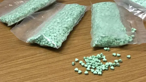 Päckchen mit grünen Ecstasy-Tabletten liegen auf einem Tisch.