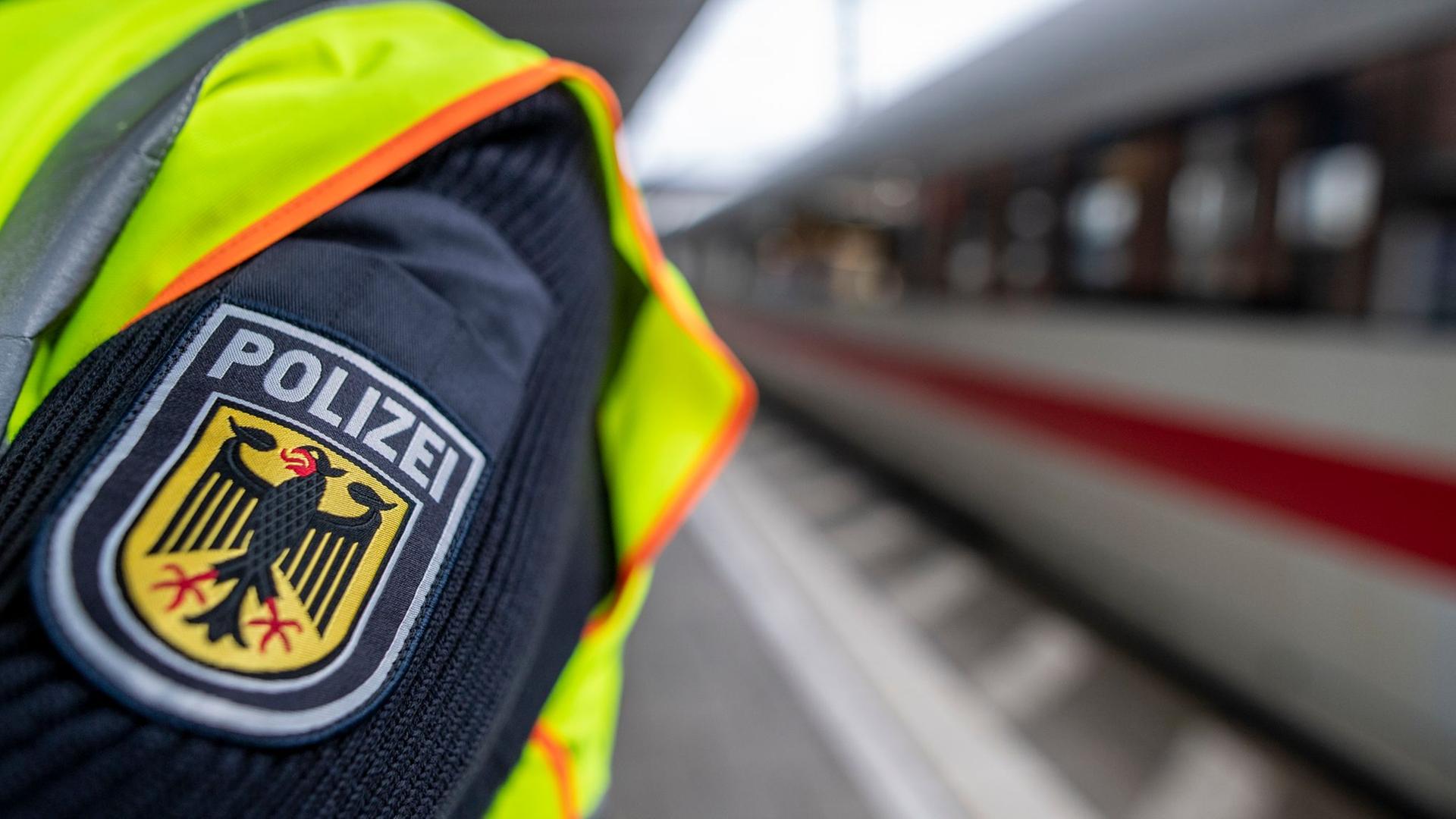 Ein Bundespolizist steht in einem Bahnhof vor einem ICE. | Patrick Seeger/dpa