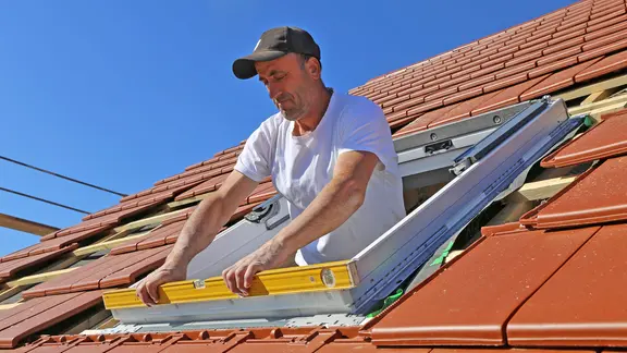 Ein Handwerker baut ein neues Dachfenster ein.