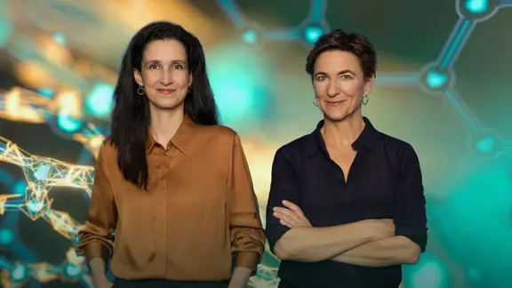 Beke Schulmann und Korinna Hennig stehen vor einem abstrakten, wissenschaftlich anmutenden Hintergrund mit leuchtenden Molekülstrukturen. Beide blicken freundlich in die Kamera.