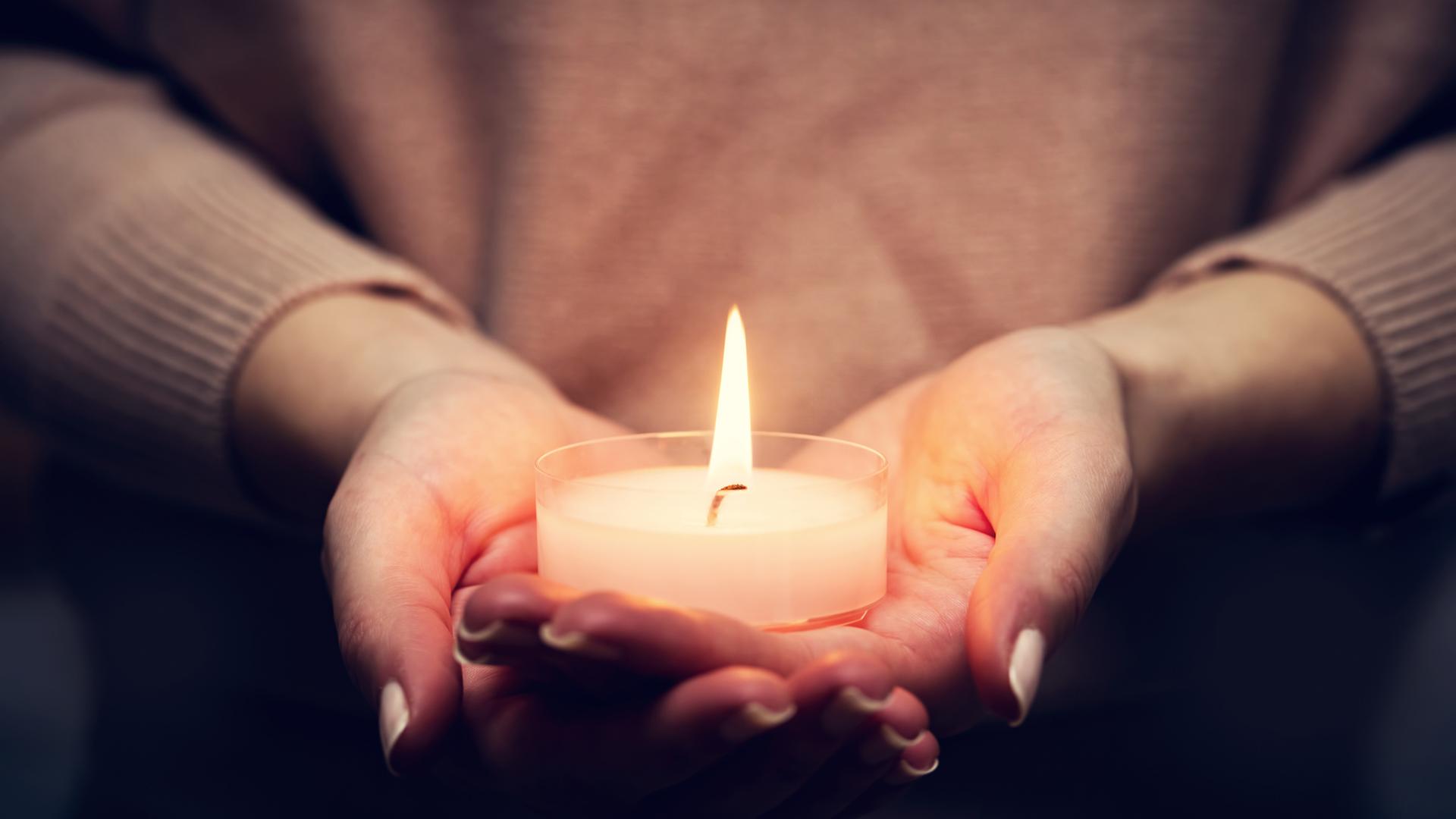 Eine Frau hält eine Kerze in ihren Händen | Photocreo Bednarek