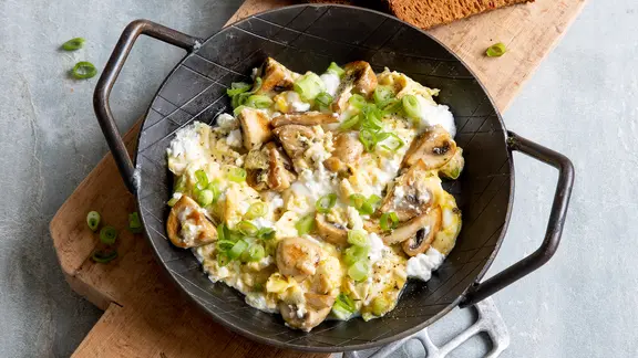 Eine Pfanne mit Rührei mit Hüttenkäse und gebratenen Pilzen. | ZS-Verlag, Claudia Timmann Eine Pfanne mit Rührei mit Hüttenkäse und gebratenen Pilzen.