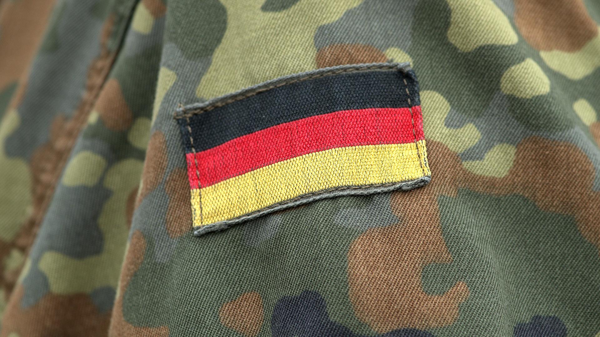 Der Aufnäher einer Deutschlandflagge auf dem Camouflage-Hemd eines Soldaten der Bundeswehr. | picture alliance/SULUPRESS.DE, Torsten Sukrow
