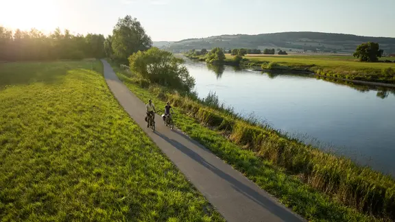 Ein Pärchen fährt auf dem Weserradweg bei Polle Fahrrad.