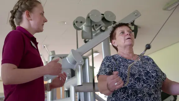 Die Patientin trainiert unter Anleitung an einem Gerät.