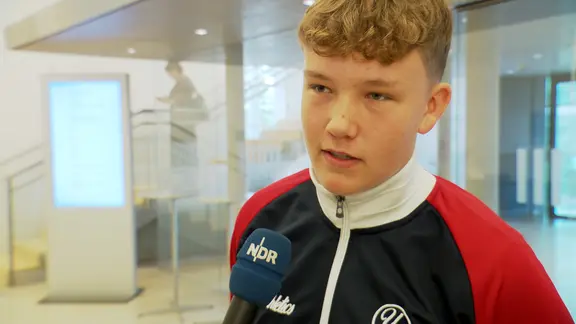 Ein Schüler steht im Foyer des Kieler Landeshauses bei einem Interview.