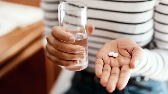 Schmerzmittel: In der Hand einer Frau liegen zwei weiße Tabletten