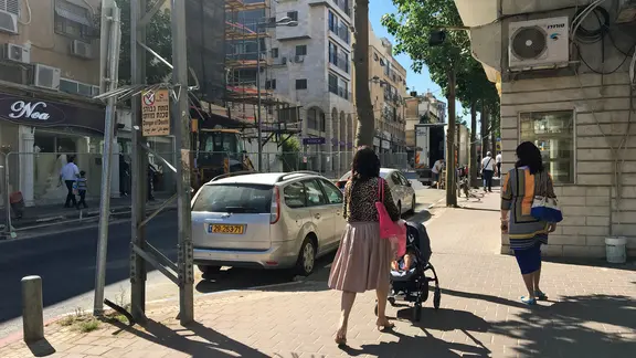 Eine Straße mit Auto und zwei Frauen in Tel Aviv.