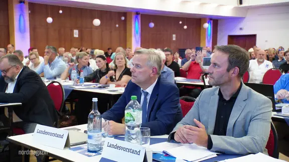 Enrico Schult (re.) und  Leif-Erik Holm, beide AfD, sitzen auf ihren Plätzen nebeneinander beim Parteitag der AfD in Demen. 