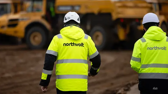 Zwei Mitarbeiter der Firma Nothvolt gehen über eine Baustelle im Kreis Dithmarschen.