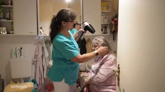 Pflegfachkraft Beate Fibinger föhnt einer Patientin die Haare.