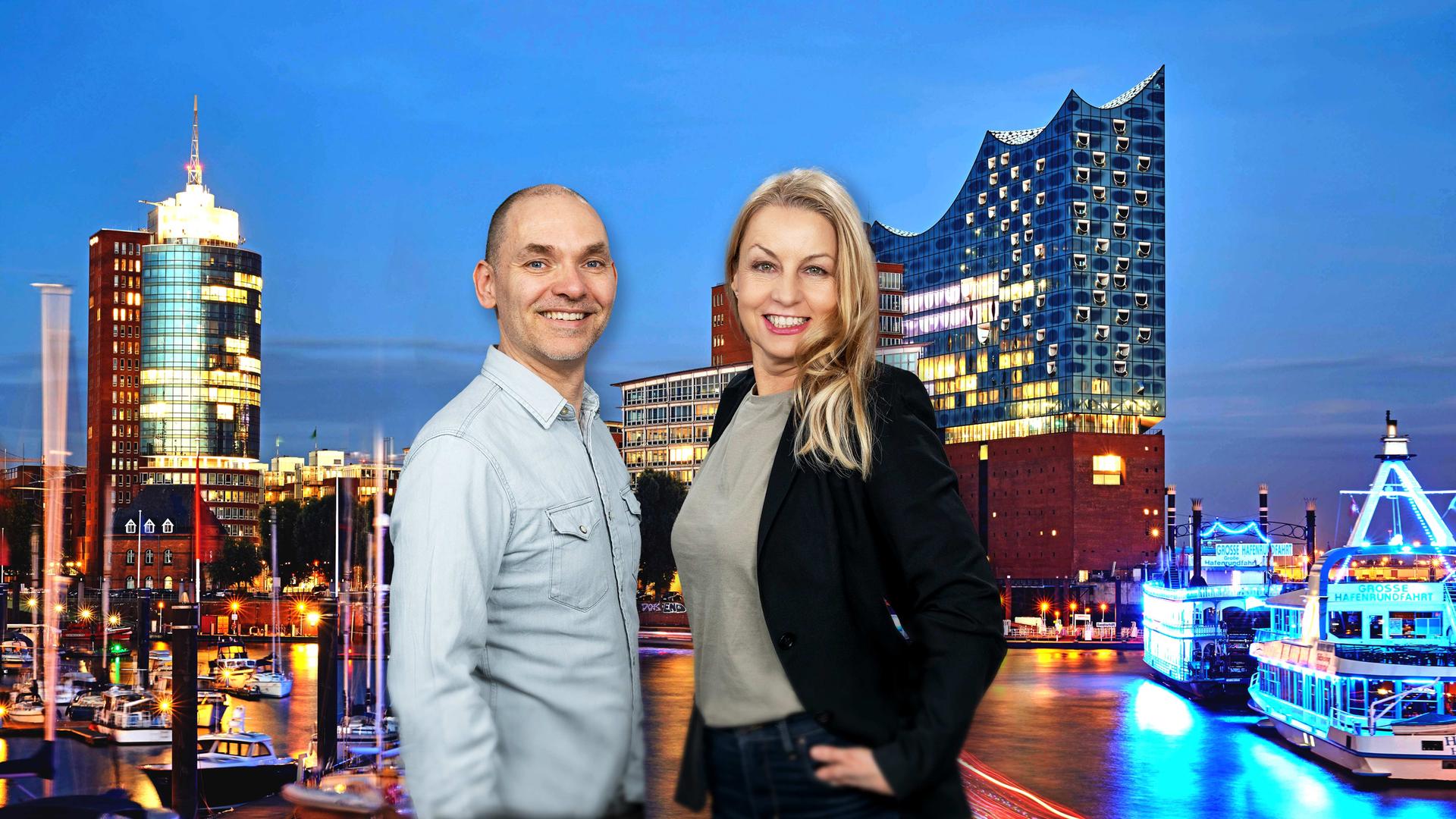 Ole Wackermann und Maiken Nielsen stehen vor einem Hintergrund, der den Hamburger Hafen und die Elphilharmonie am Abend zeigt, und lächeln in die Kamera. | NDR | picture alliance | Westend61 | Willing-Holtz | Arman Ahmadi
