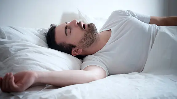 Schlafender Mann im Bett mit geöffnetem Mund. | Fotolia.com, Paolese Schlafender Mann im Bett mit geöffnetem Mund.