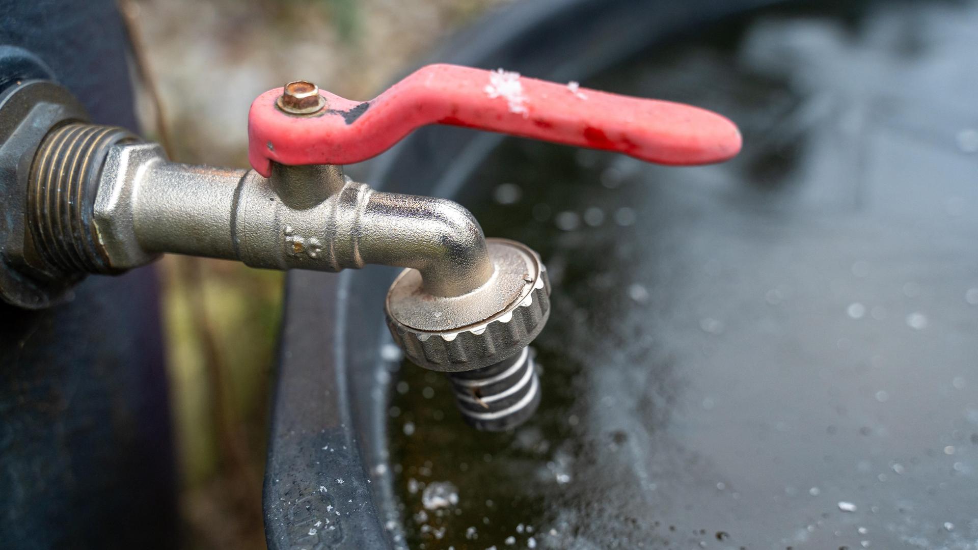 Ein gefrorener Wasserhahn über einem Wasserbehälter im Winter. | picture alliance / CHROMORANGE | Michael Bihlmayer