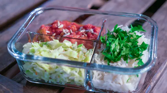 Eine Box mit Tomatenreis und mariniertem Spitzkohl zum Mitnehmen.