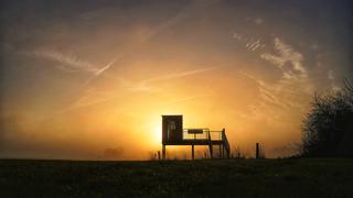 Die Sonne geht über einer Aussichtsplattform zum Vögel beobachten in Emlichheim auf.