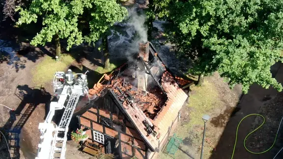 Feuerwehrleute löschen von einer Drehleiter aus ein brennendes Fachwerkhaus in Emsbüren.