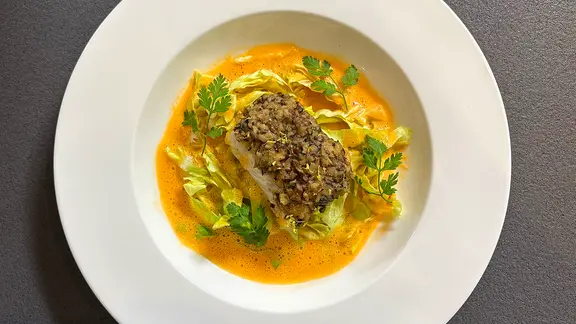 Zanderfilet mit Pilzkruste mit Kopfsalat und Schaumweinsoße auf einem weißen Teller | NDR Zanderfilet mit Pilzkruste mit Kopfsalat und Schaumweinsoße auf einem weißen Teller