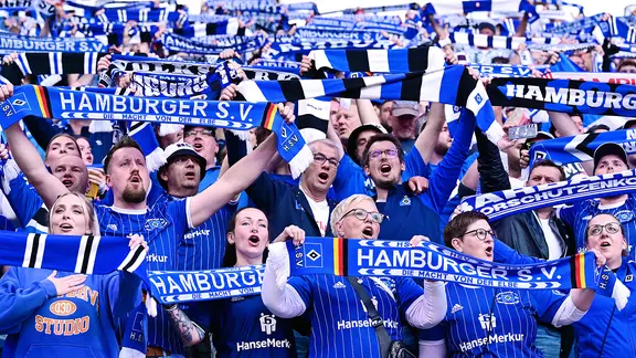 Jubelnde HSV-Fans halten Schals hoch.
