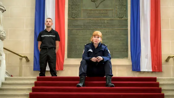 Szenenbild aus der französischen Serie "HIP: Ermittlerin mit Mords-IQ": Morgane sitzt in Uniform auf einer Treppe.
