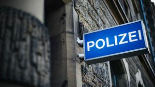 An einer Hausfassade hängt ein Leuchtschild mit der Aufschrift Polizei.